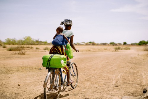Barry Aliman, 24, va en su bicicleta con su bebé a recoger agua para su familia cerca de Boromo, Burkina Faso. Una nueva herramienta en línea apunta a presentar un panorama claro de cómo los bosques contribuyen a las estrategias de adaptación climática de la población rural. Foto Ollivier Girard/CIFOR.