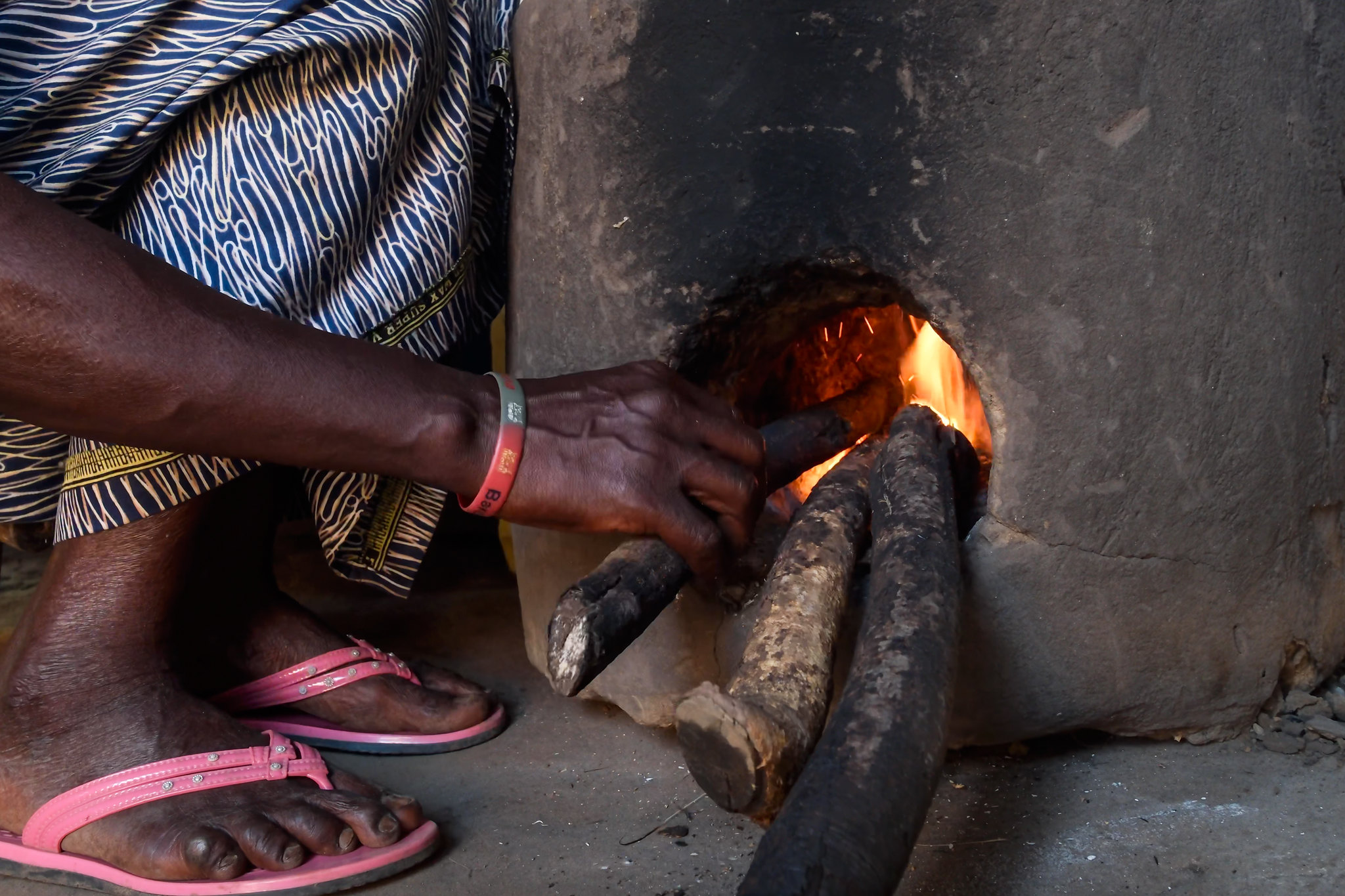 A person places pieces of wood into a household cookstove in the Democratic Republic of the Congo.