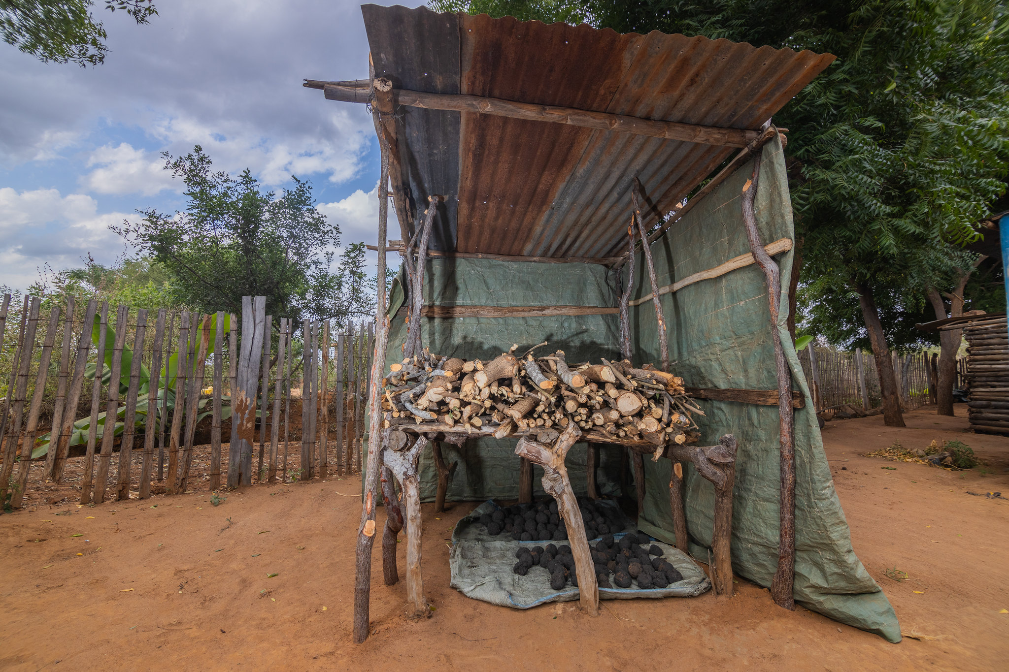 A stack of fuelwood is stored under a simple shelter in Kenya.