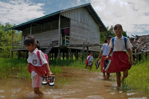 Los estudiantes deben quitarse los zapatos antes de salir de clase durante la temporada de lluvias, cerca del lago Sentarum, Kalimantan Occidental, Indonesia. Una investigación en curso trata de establecer cómo los bosques afectan la sensibilidad de las personas a eventos climáticos tales como inundaciones, así como su capacidad de adaptación para responder a ellos. Fotografía de Ramadian Bachtiar / CIFOR.