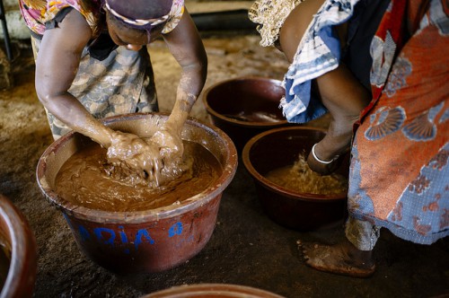 Once roasted, Rabo Nafissatou (left) and Bassia Mariam (right) ground the shea nuts to a paste, mix it with water and beat it, Burkina Faso. 