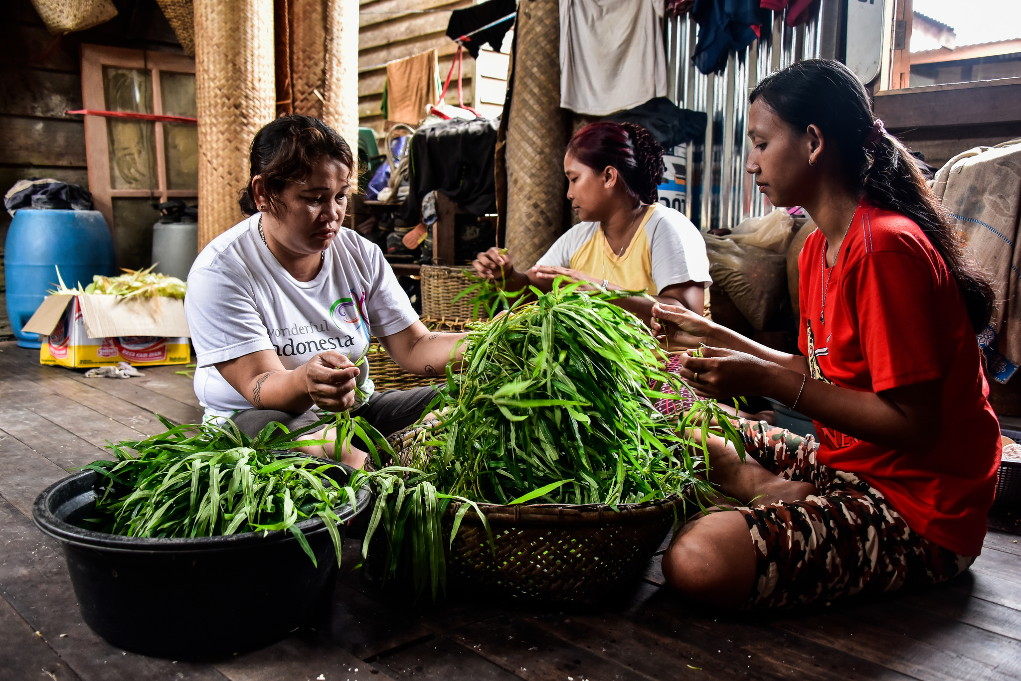 Changing diets, malnutrition, food security, Three Indonesian women prepare a pile of green vegetables for dinner in the vilage