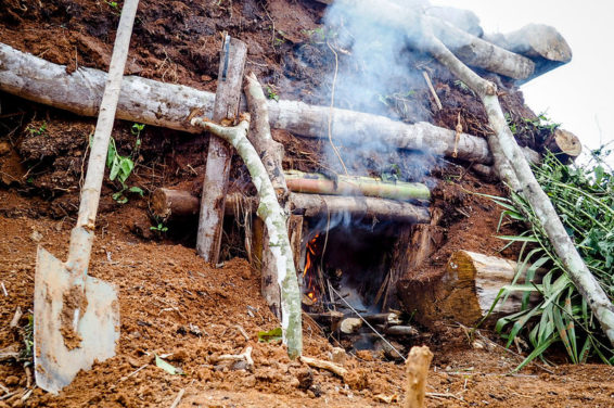 A mound under which smoke from smoldering charcoal burns