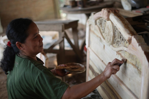 A woman applies filler to gaps in wood