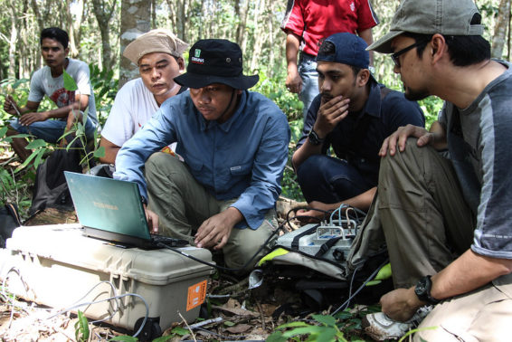 Scholars look at a laptop screen in the Indonesian peatlands