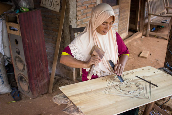 Woman chisels a design into wood