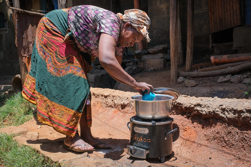 A woman cooks in a pot on an outdoor stove