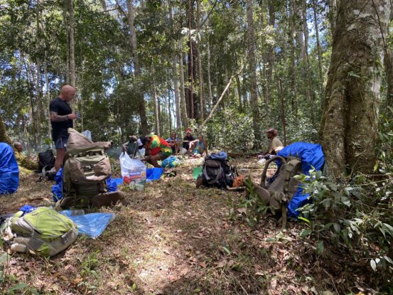 Expedition team resting in the forest on the trail to the WWII Flying Dutchman wreck in Papua New Guinea’s Owen Stanley Range.