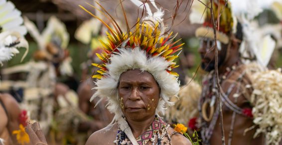 Man wearing a traditional feather headdress at a cultural festival on the Managalas Plateau, illustrating the role of feather harvesting in Papua New Guinea.