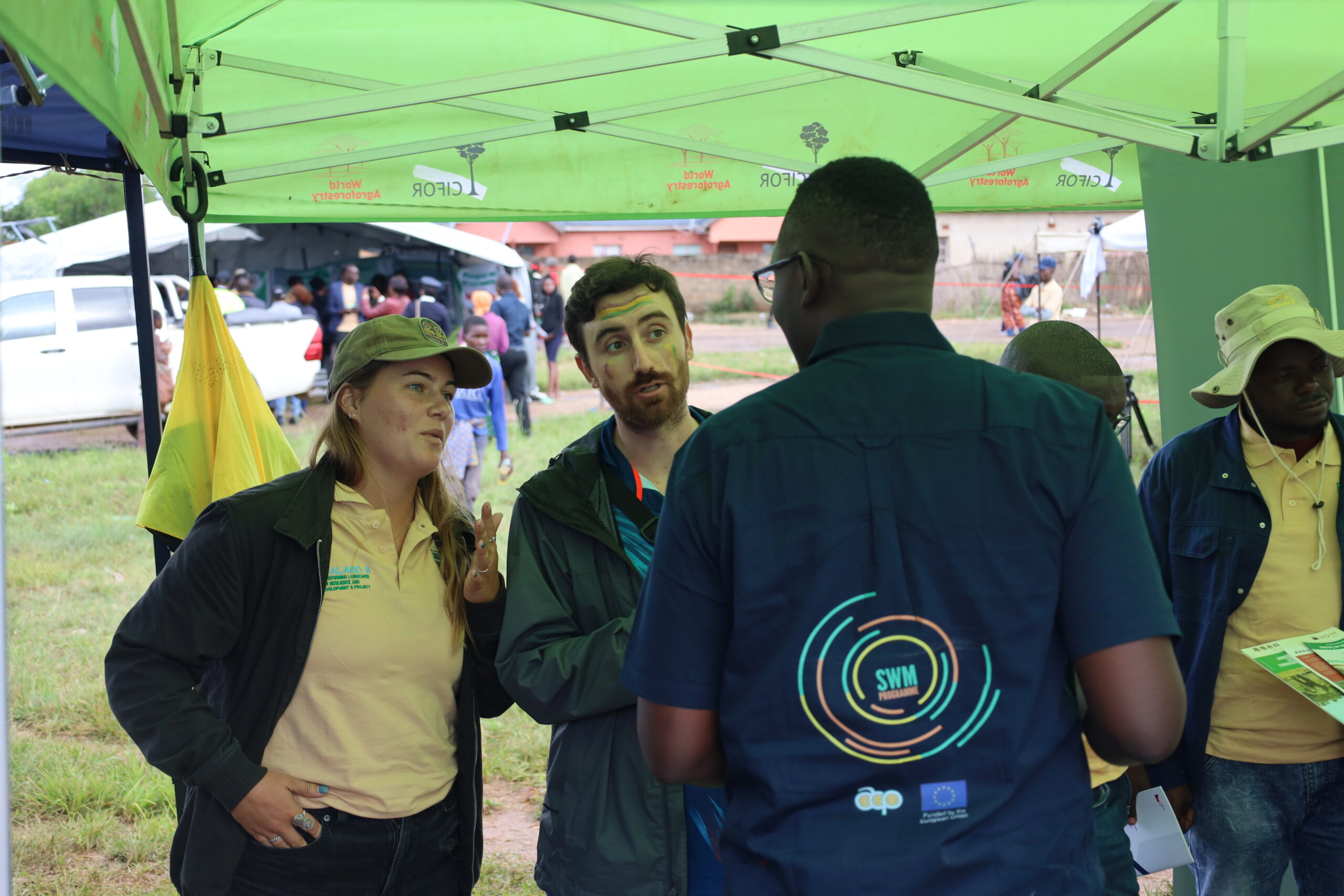 Daniel Phiri speaks with visitors beside the SWM Programme exhibition stand.