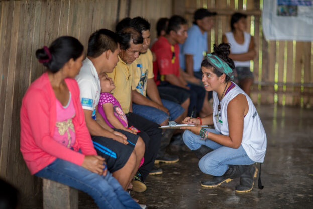 Community members speak with a CIFOR team member inside a wooden community building in Cashiboya, Loreto, Peru.