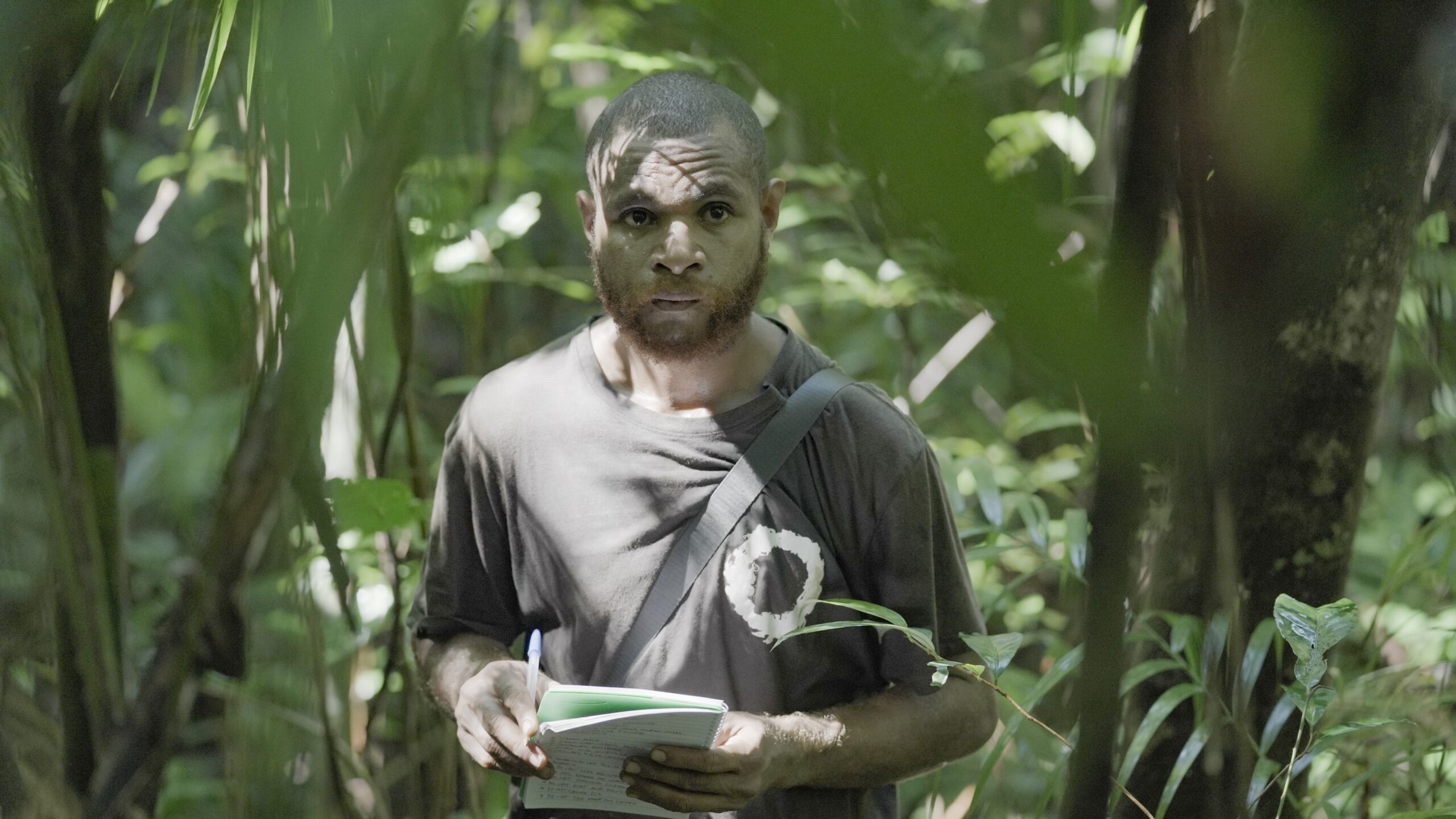 Biodiversity Team Leader Alpheus Mamo records bird observations in a notebook while conducting a wildlife monitoring survey in the forest of Papua New Guineaโs Managalas Conservation Area.