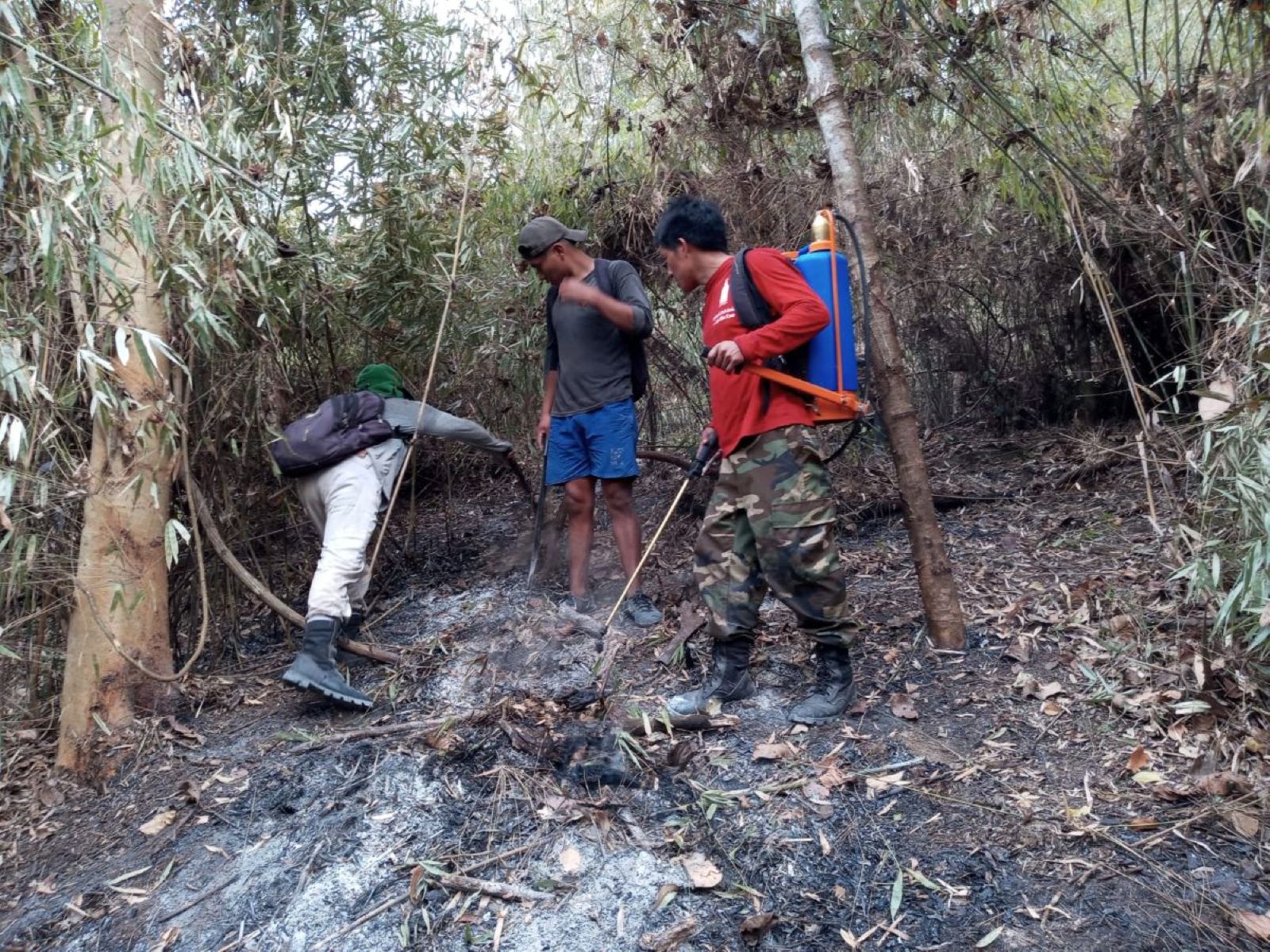 Asháninka community members use hand tools and backpack water sprayers to contain a forest fire in the Peruvian Amazon.