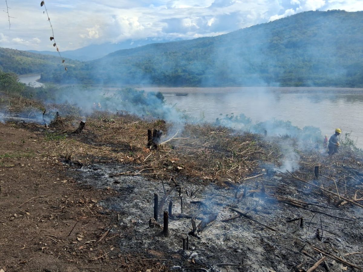 Smoke rises from a controlled agricultural burn beside the Ene River as part of traditional Asháninka land preparation.