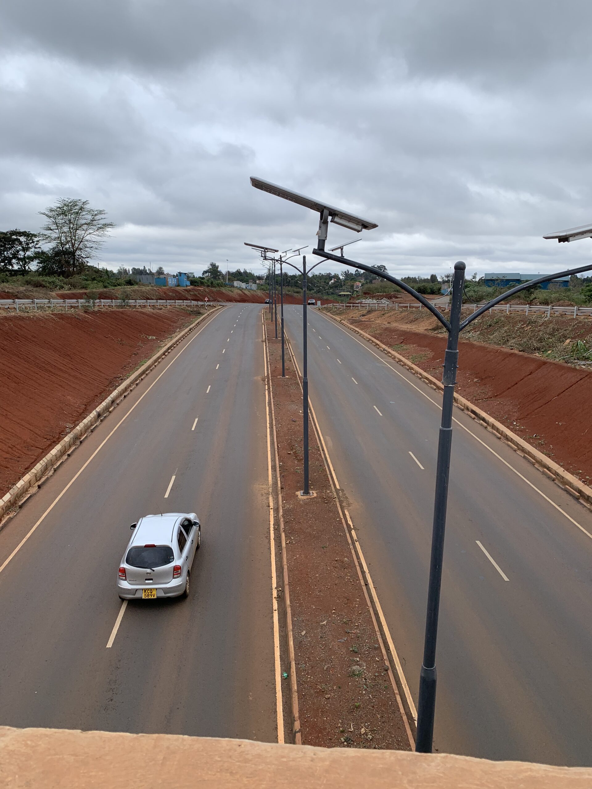 Bare red-soil slopes beside a newly constructed paved road in October 2019.