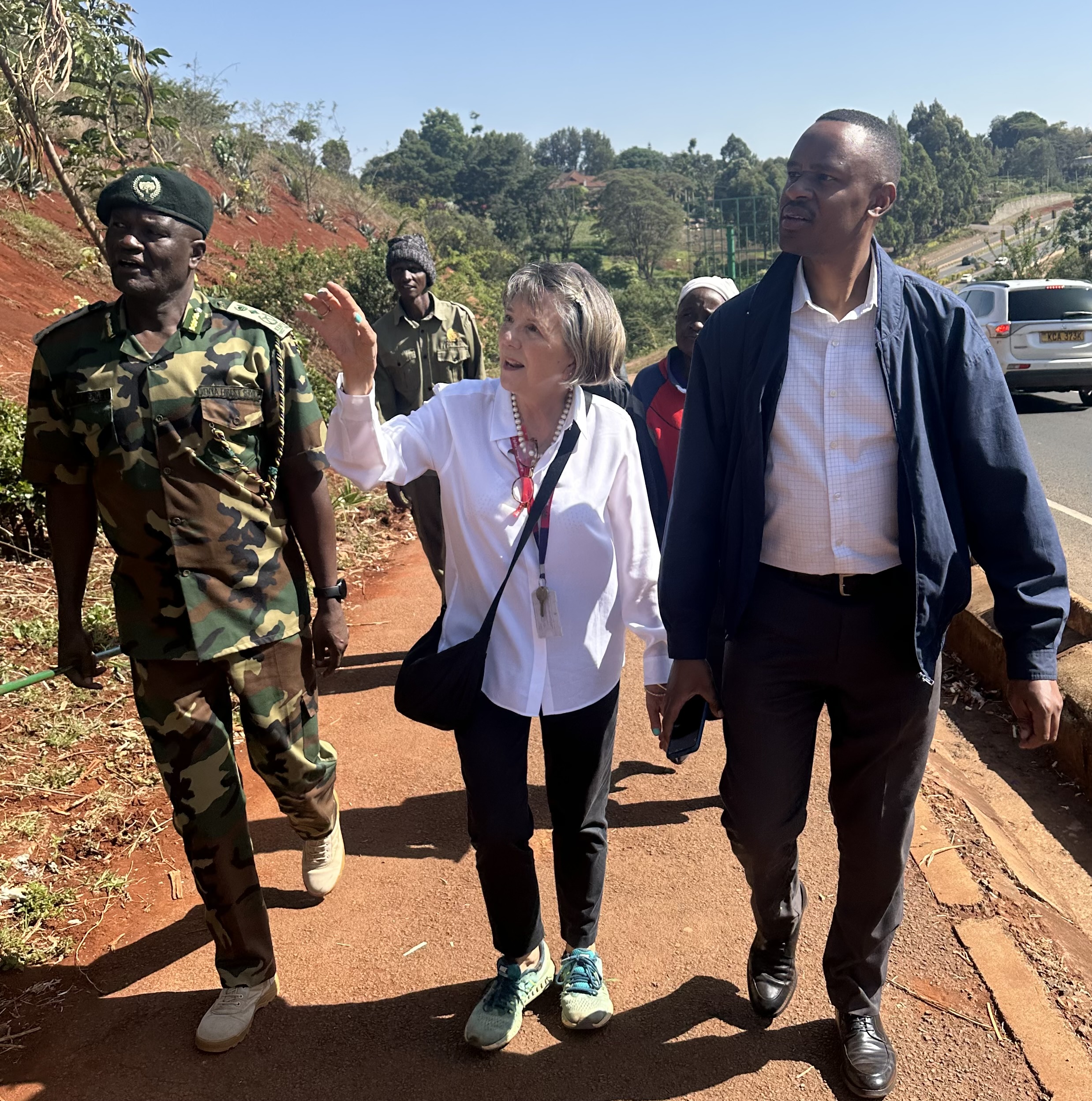 Cathy Watson walks along a roadside with Dr. Clement Ng’oriareng and other people during a tour of the link road.