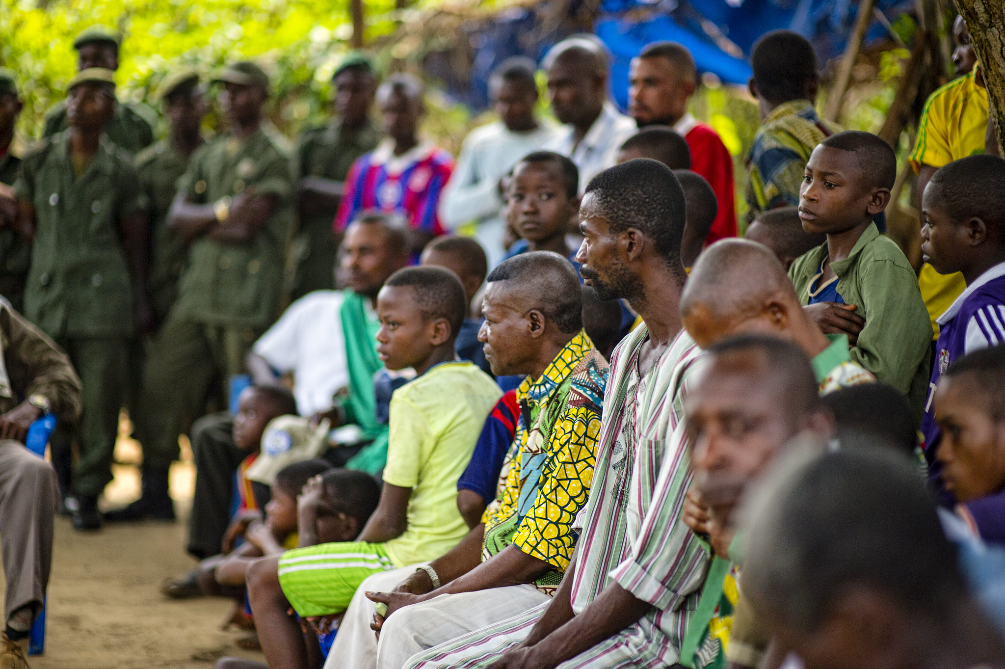 Community members seated outdoors during a sensitization meeting in the Democratic Republic of the Congo.