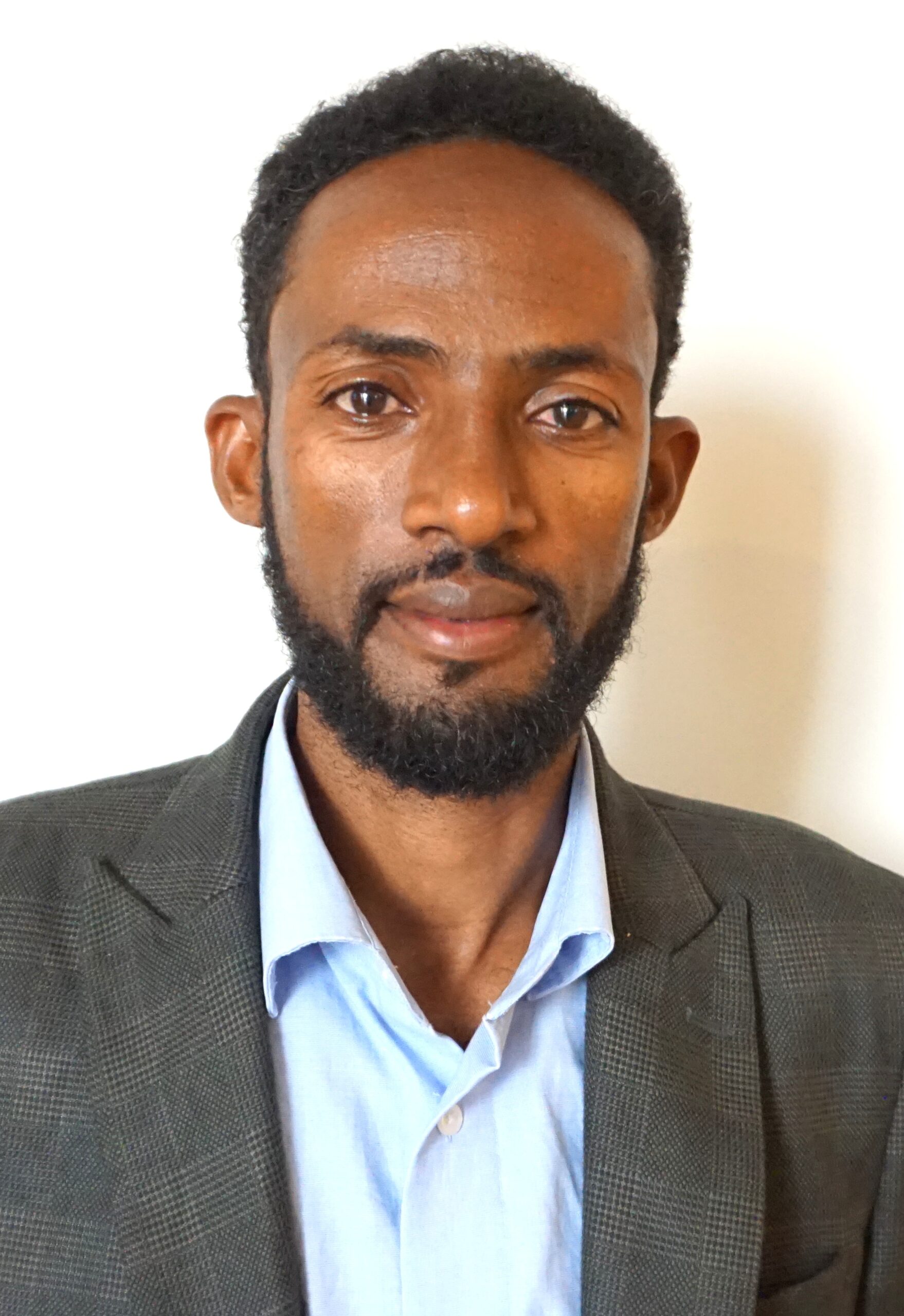 Portrait of Bizuayehu Alemu, wearing a grey jacket and light blue shirt.