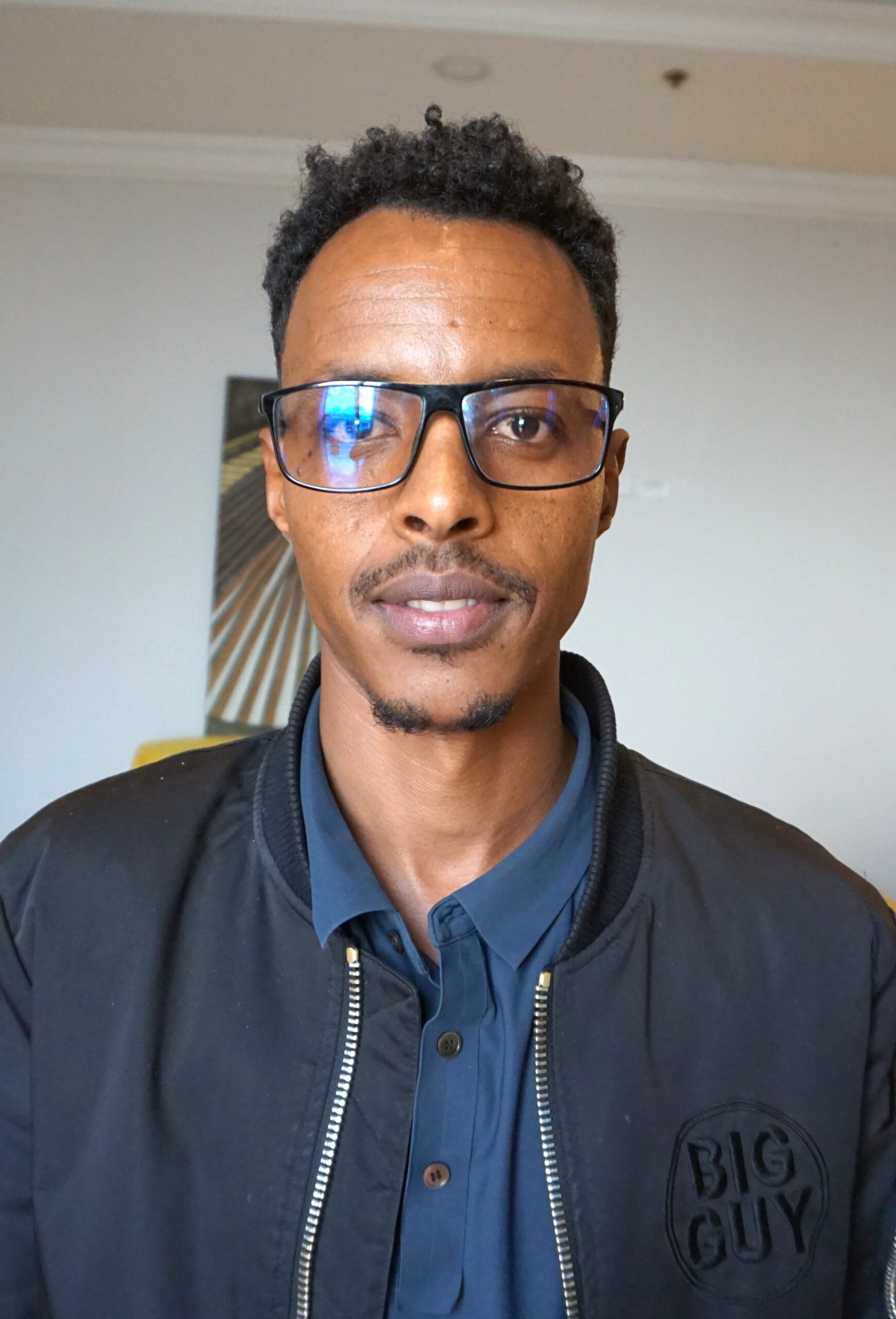 Portrait of Yikuno Amlak Gebre Wahid wearing glasses and a dark jacket.