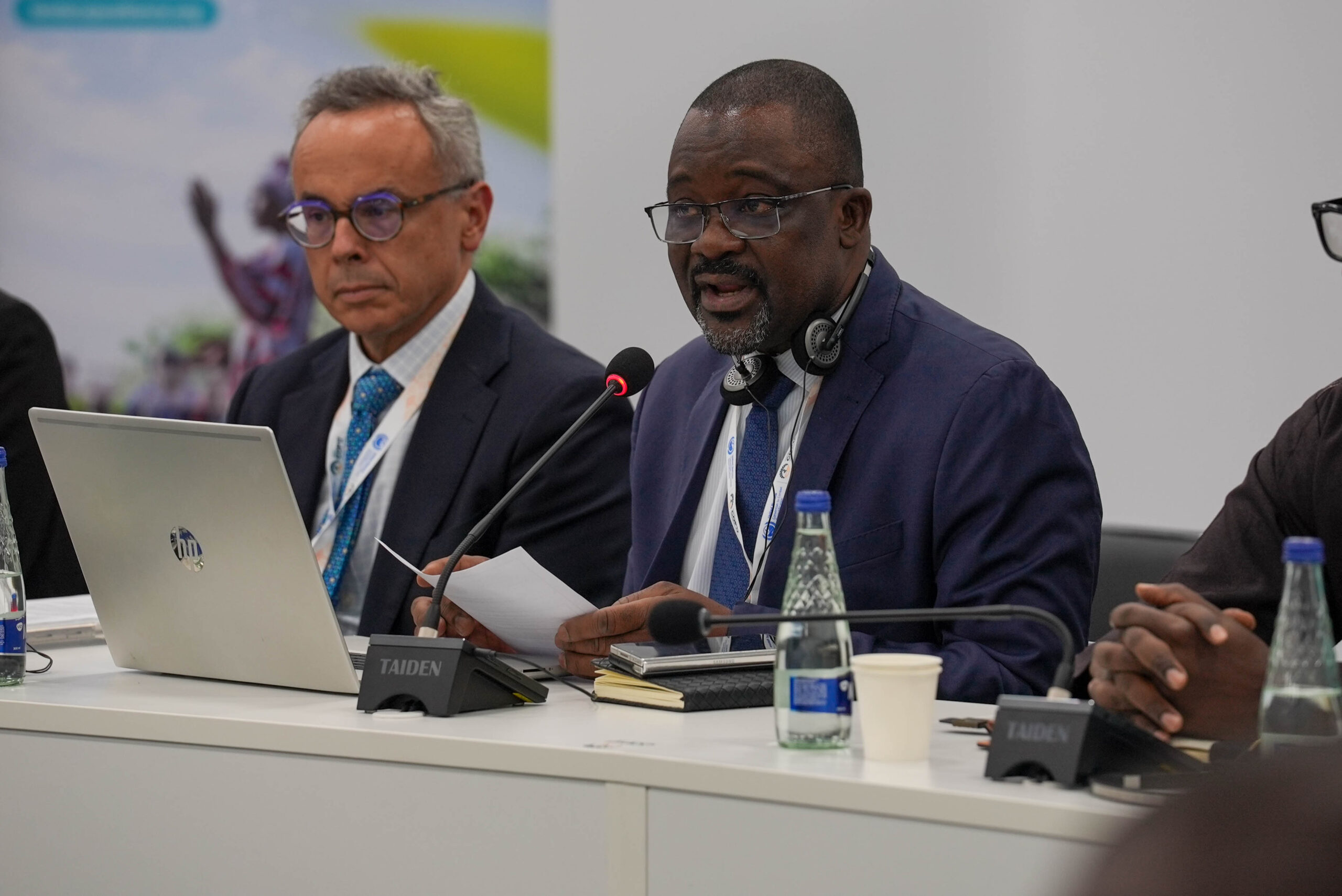Almoustapha Garba speaks during a session at UNCCD COP17 in Ulaanbaatar, Mongolia, seated at a panel table with a microphone and laptop.