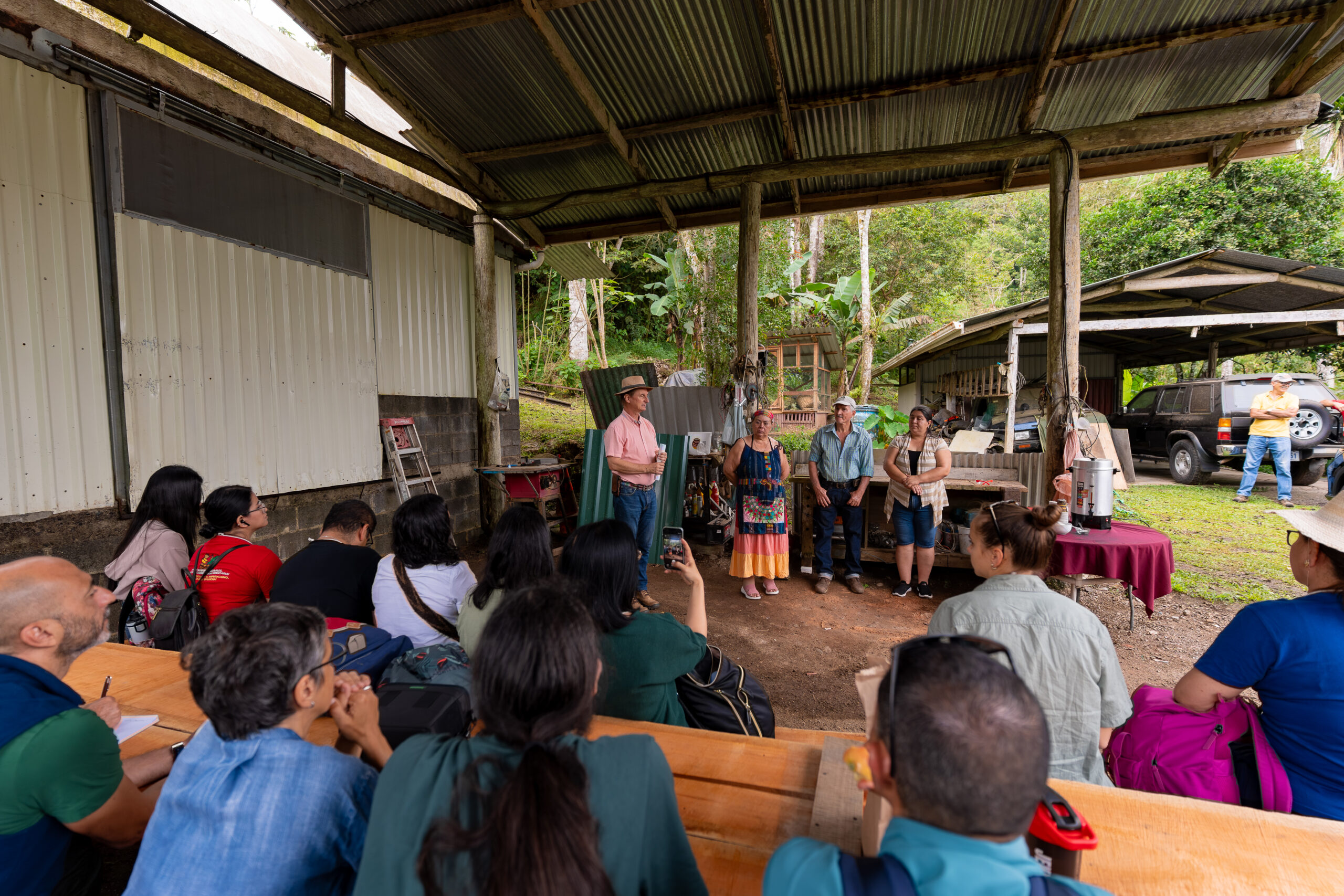 Farmers speak to a seated group of forum participants in a covered outdoor area at Los Helechos Farm.
