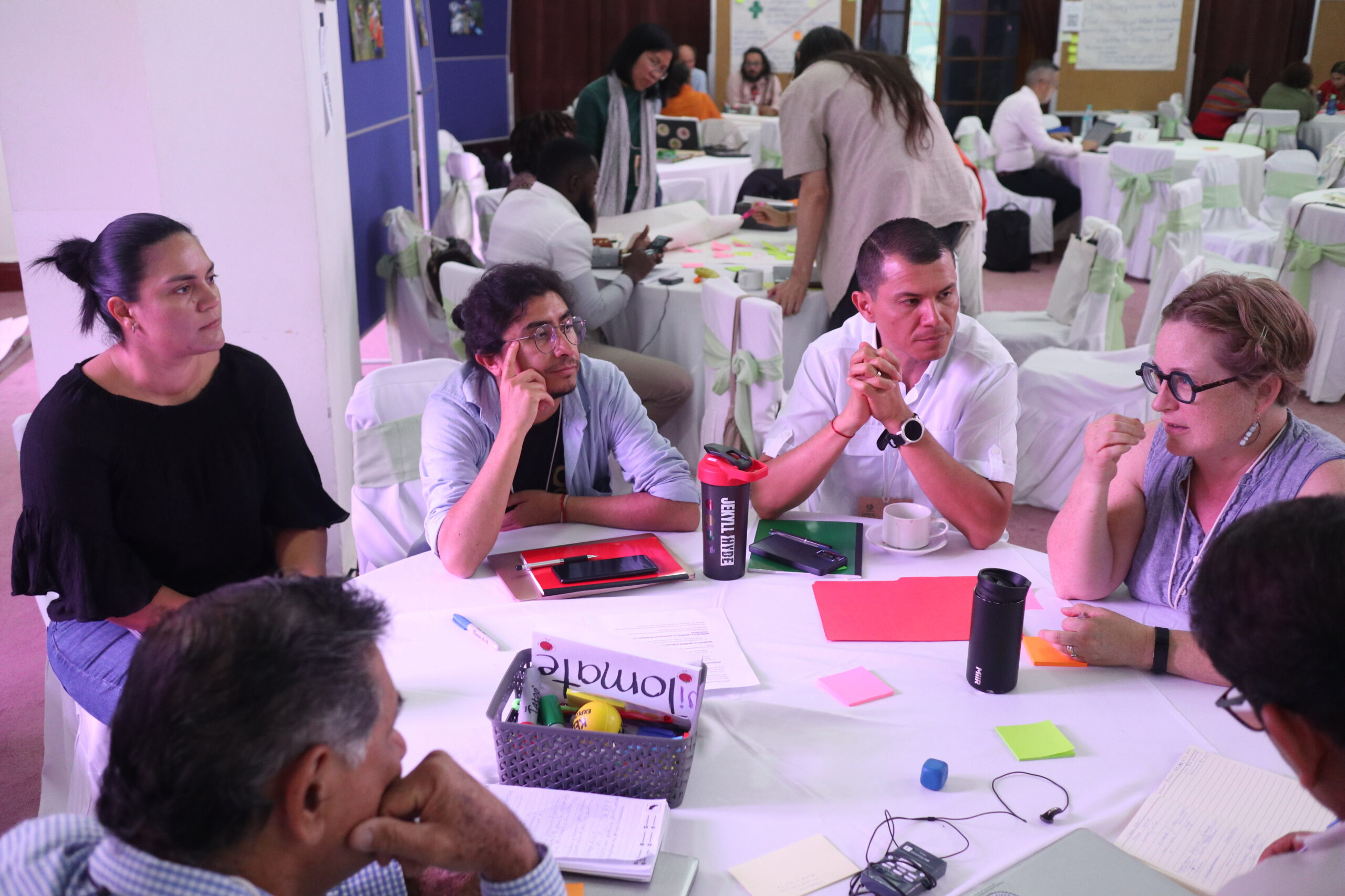 Forum participants sit around tables during an interactive group session, discussing and taking notes.