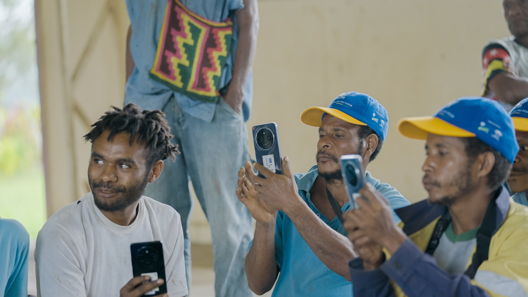 Participants hold smartphones as they practise taking photographs and recording videos during a communications training session.