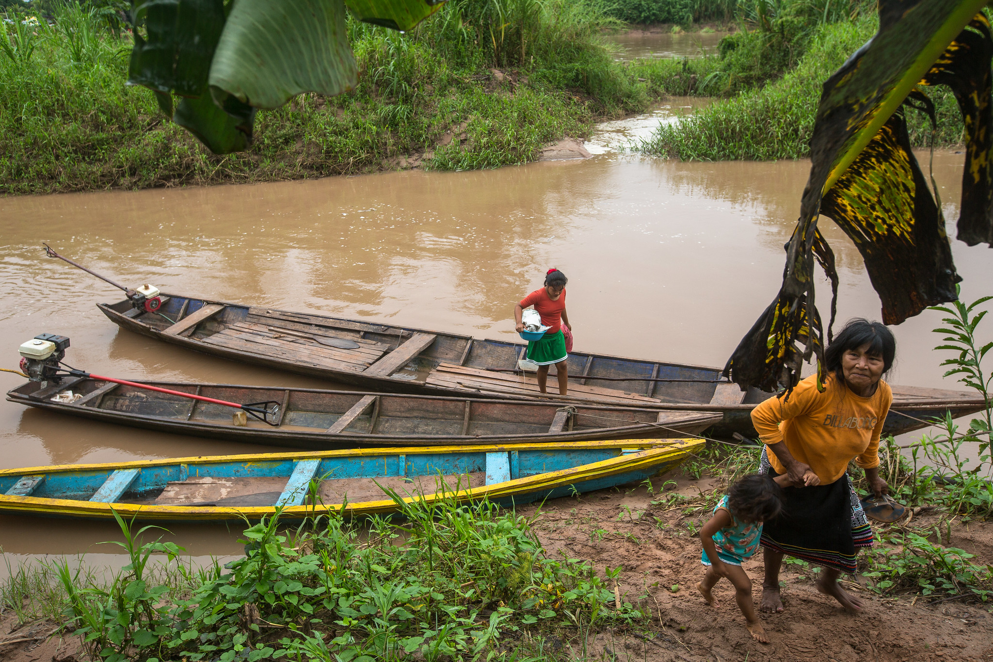 Family arriving by canoe along a river in the Peruvian Amazon