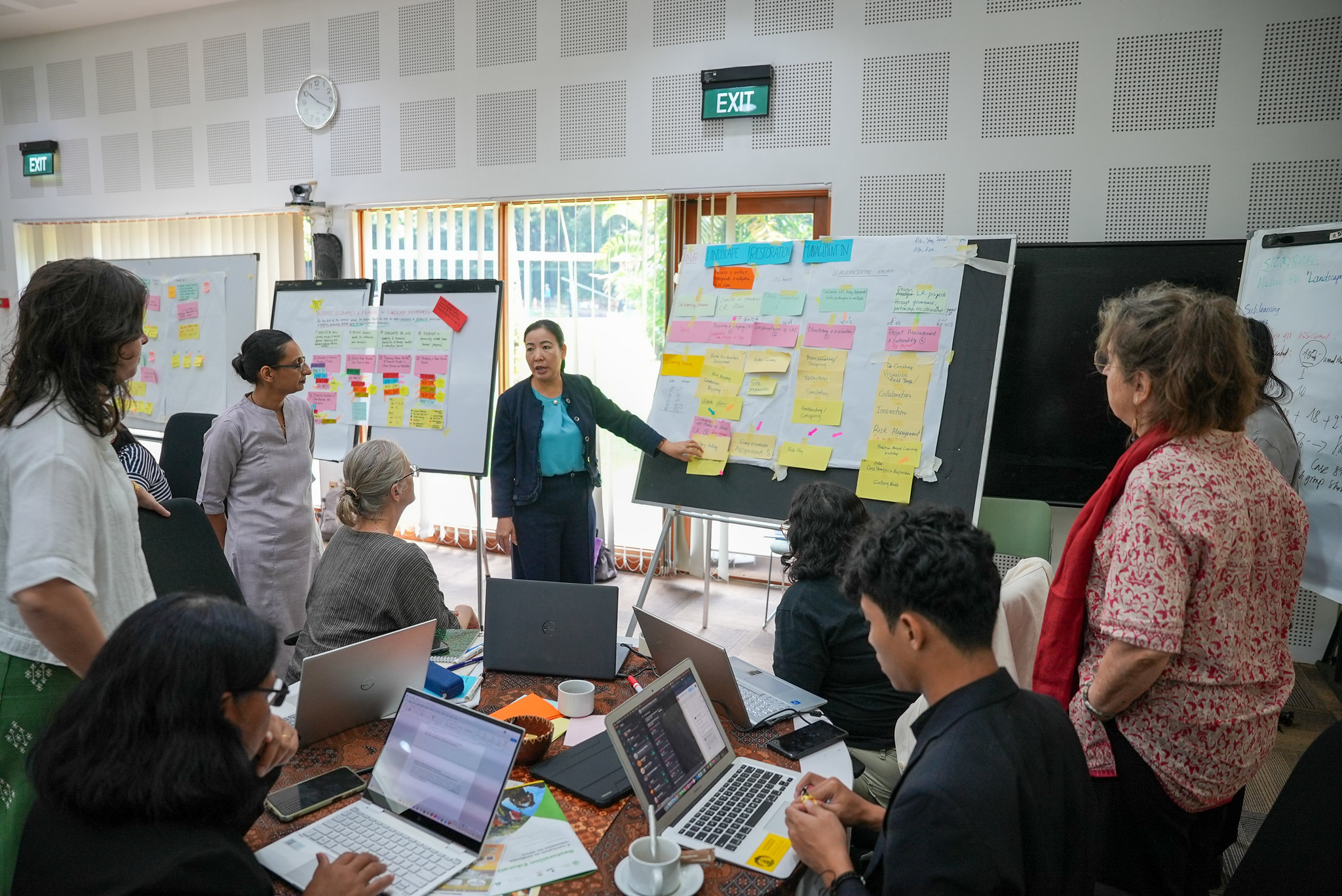 Participants gathered around a board presenting and discussing notes during a restoration education workshop at CIFOR-ICRAF Bogor campus.