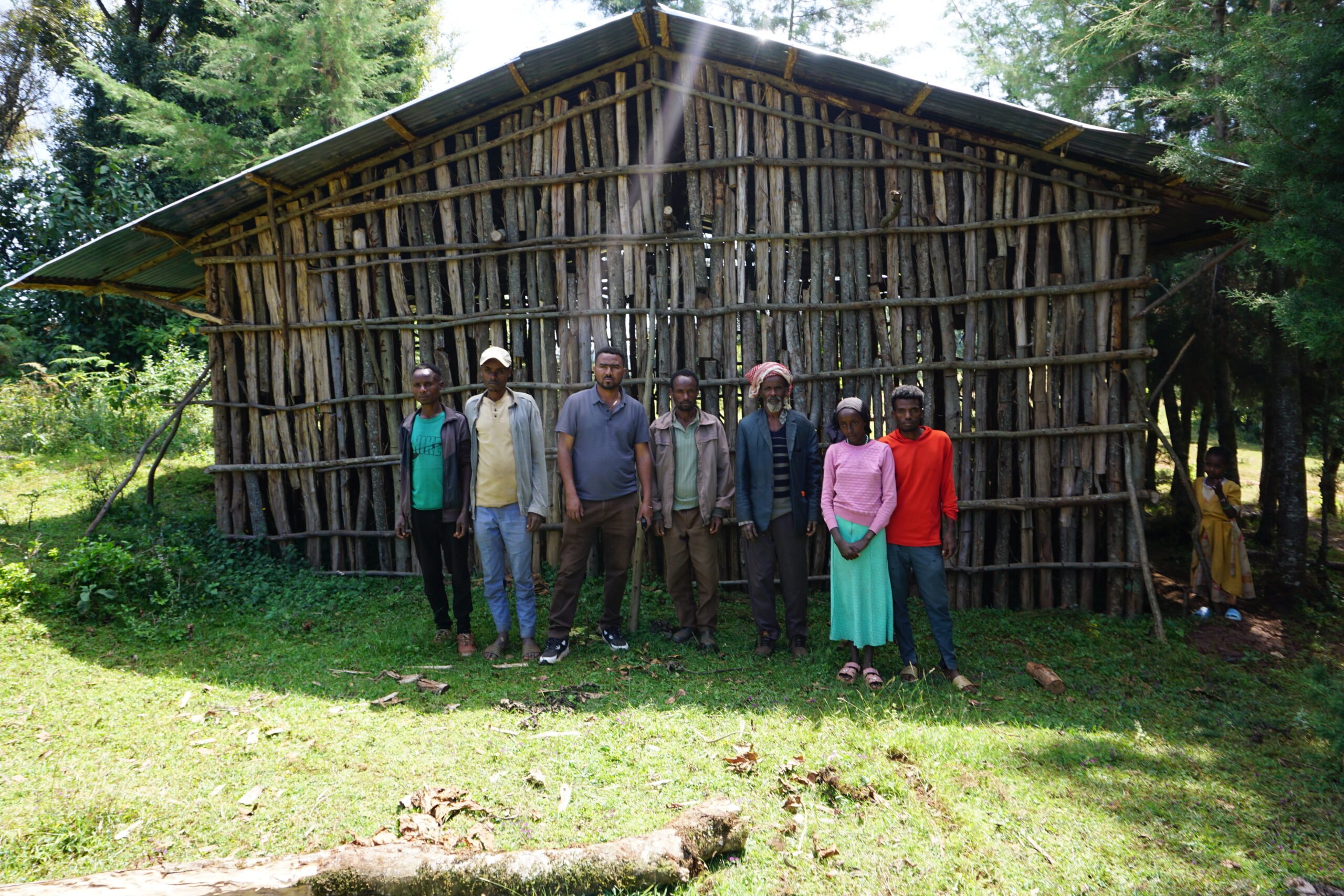 Youth cooperative members standing together in front of a wooden building in southwest Ethiopia