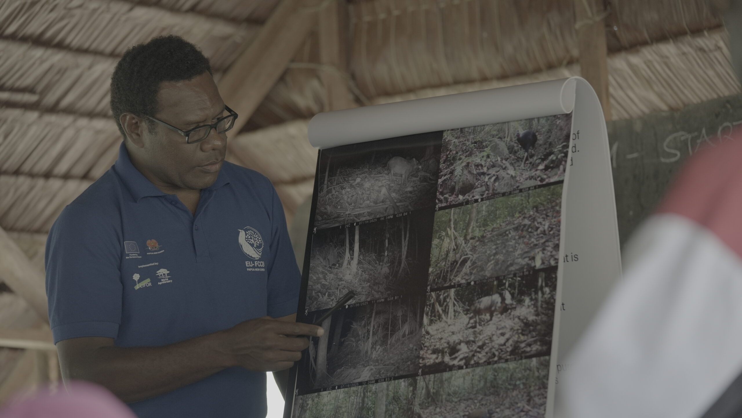 Ecologist presenting camera-trap images of wildlife during the Combined Forum in Kawowogi Village on the Managalas Plateau in Papua New Guinea.