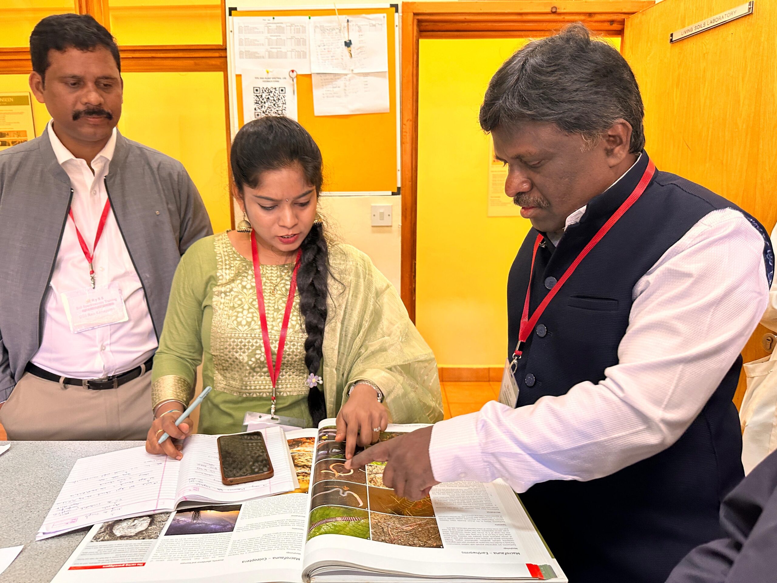 Training participants reviewing soil samples and reference materials during a soil analysis session in Kenya.