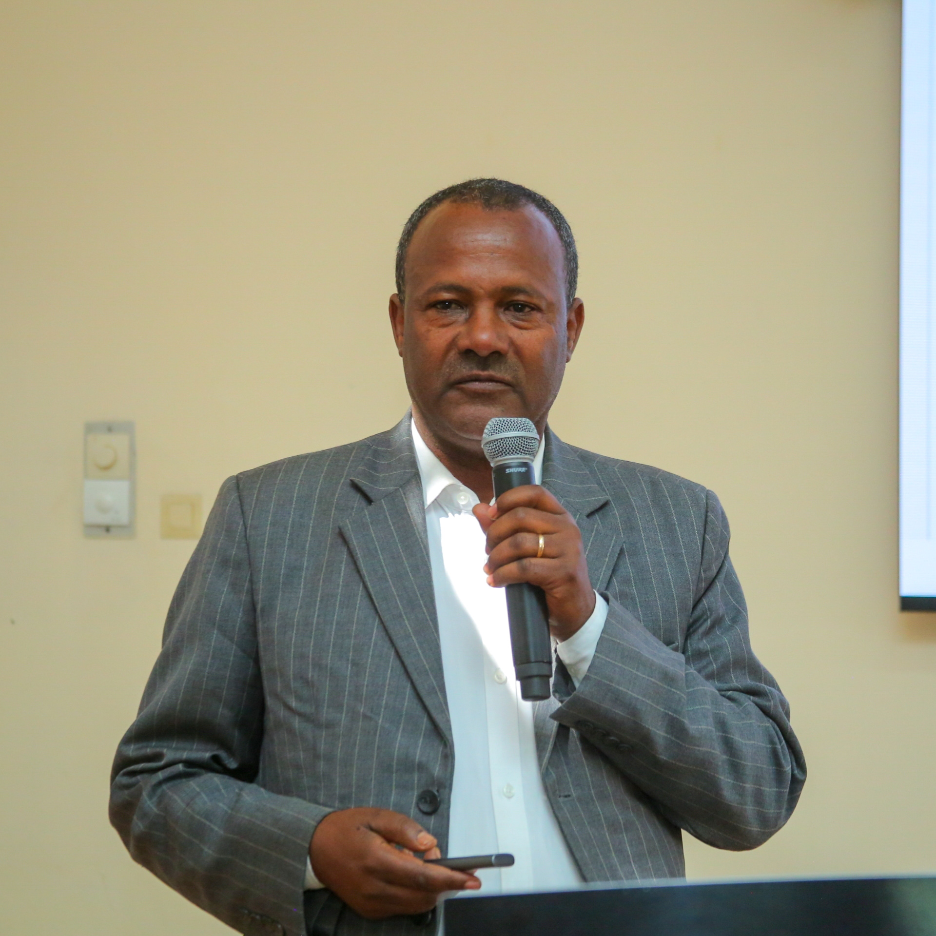 Dr. Zenebe Adimasu speaks into a microphone during a presentation at the national validation workshop for Ethiopia’s National Agroecology Strategy.